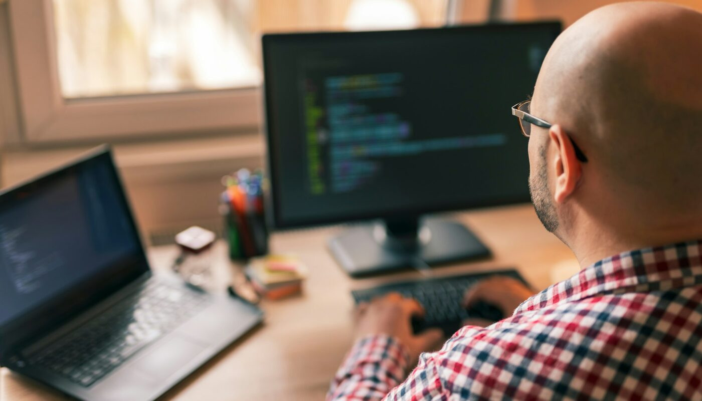 Programmeur masculin travaillant au bureau à domicile, assis à son bureau et codant